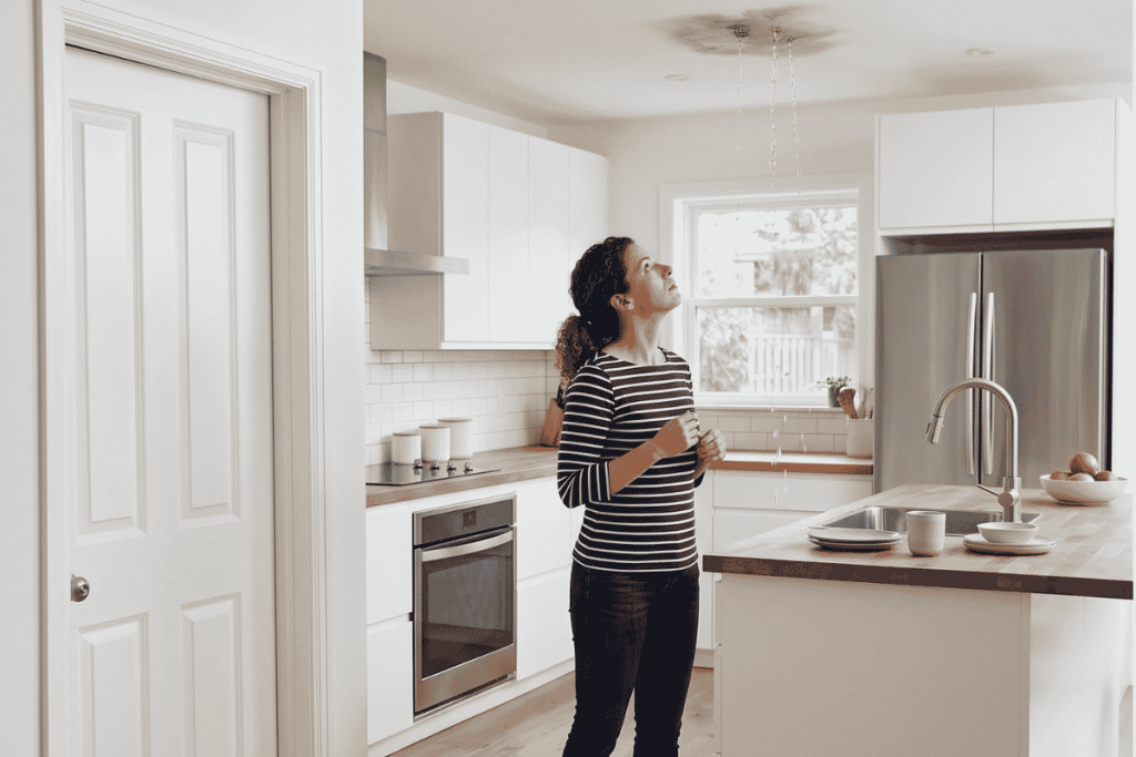 Women is looking at the leak in her ceiling, and needs an emergency plumber